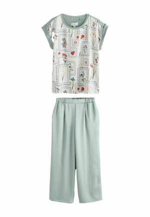 Kurzärmlige Bluse mit botanischen Prints und hellgrünen, weit geschnittenen Hosen mit elastischem Bund, flach auf weißem Hintergrund dargestellt.