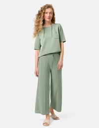 Light green short-sleeve top with a front pocket and drawstring pants featuring wide legs. Smooth texture, casual design, and minimal hardware.