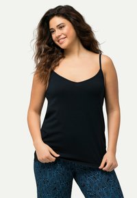 Černý top na ramínka s tenkými popruhy, design s V-výstřihem, vyrobený z měkkého materiálu. V kombinaci s modrými legínami s vzorem paisley.