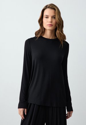 Long-sleeve black top made of soft fabric, featuring a round neckline and relaxed fit with a smooth texture and minimal design.