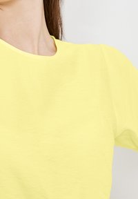 T-shirt giallo a maniche corte realizzato in tessuto morbido, con scollatura rotonda, texture liscia e vestibilità comoda.