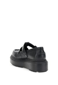 Zapatos de cuero negros con una suela gruesa y un diseño de tira ancha. Textura suave con detalles de costura a lo largo de los bordes.