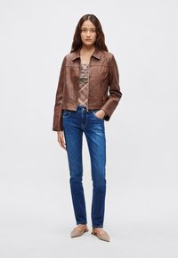 Ruda odinė su trumpu kirpimu striukė su smakro apykakle, derinama su mėlynomis siauro pjūvio džinsomis ir smėlio spalvos balerinomis. Tekstūruota medžiaga, priekinis užtrauktukas.