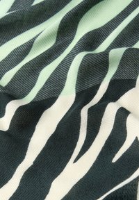 Flerfärgad tyg med vågiga mönster i mörkgrön och mjuk mint, med en texturerad väv och en slät yta.