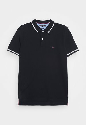 Polo noir à manches courtes avec col rayé blanc et bords de manches, patte de boutonnage à deux boutons et petit logo drapeau sur la poitrine.