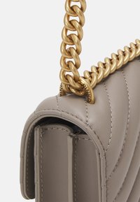 Borsa a tracolla in pelle grigia con un design trapuntato. Presenta una catena dorata chunky e dettagli di cucitura visibili. Texture liscia.