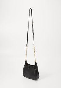 Borsa a mano in pelle nera con forma curva, catena dorata e tracolla in pelle, con chiusura a patta e superficie testurizzata.
