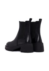 Bottines en cuir noir avec panneaux élastiques sur les côtés, talons épais et semelle texturée. Fini lisse avec un aspect mat.
