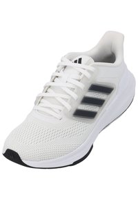 Scarpa sportiva bianca con tomaia in rete, lacci piatti e tre strisce nere di lato. Suola liscia con un leggero accento nero sulla punta.