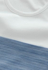 Bomulds T-shirt med rund halsudskæring, der har et vandret opdelt design: hvid øverste del og en struktureret lys blå nederste del.