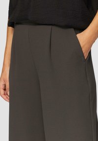 Donkergrijze trousers van soepel materiaal, met zijzakken, een relaxte pasvorm en subtiele plooien bij de tailleband.