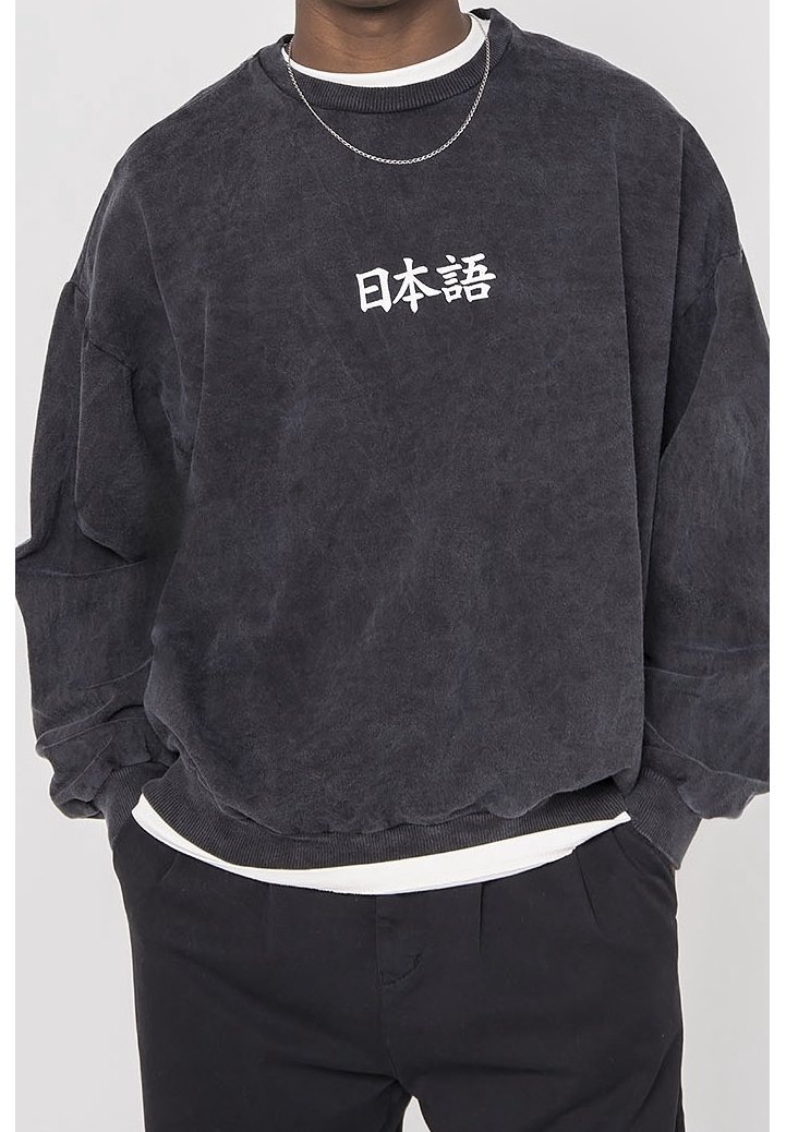Černá oversized mikina s bílými japonskými znaky na prsou, nošená přes bílou košili, spárovaná s černými kalhotami a stříbrným řetízkem.