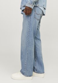 Lichtblauwe denim wijde spijkerbroek met rafelige zoom, contrasterende stiksels en ruime pasvorm. Gecombineerd met witte sneakers.
