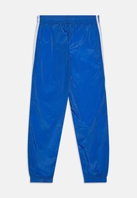 Siniset, kevyet urheiluhousut, joissa on sileä pinta, joustava vyötärö ja valkoiset sivuraidat. Kapeat lahkeet, joissa on joustavat hihnat.