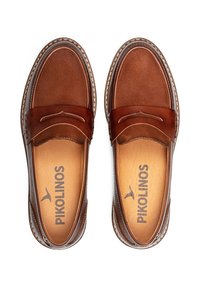 Mocasines de cuero marrón con un acabado suave y una costura decorativa. El interior cuenta con un forro beige con la marca "Pikolinos". Diseño clásico.