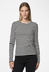 Langarm gestreept shirt in zwart-wit geribbeld materiaal met een ronde hals en een getailleerde pasvorm, gecombineerd met zwarte broeken.