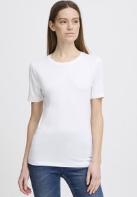 Bílý tričko s krátkým rukávem vyrobené z měkké bavlny, s kulatým výstřihem a elegantním designem. Vytvořeno v kombinaci s modrými džíny.