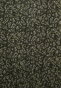 Tecido preto com um padrão floral, apresentando pequenas flores brancas e amarelas, entrelaçadas com desenhos em paisley contornados a preto.