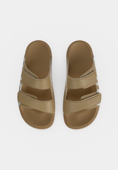Paire de sandales beiges à enfiler avec deux brides réglables, large semelle intérieure et semelles légèrement profilées, vues de dessus sur fond blanc.