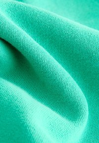 Turquoise knitted fabric, showing fine texture with a smooth surface. The material has a consistent color and subtle variations in shade.