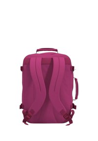 Vaaleanpunainen reppu, jossa on pehmustetut olkaimet, yläkahva, teksturoitu kangas, sivutasku vetoketjulla ja säädettävät hihnat turvalliseen kantamiseen.