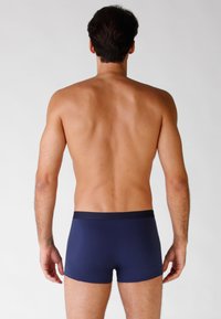 Boxer da uomo blu navy con design solido, vita elastica e texture del tessuto morbida. Mostrati da dietro su uno sfondo chiaro.
