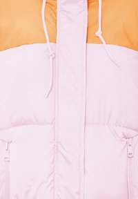 Giacca a vento con la parte inferiore rosa e la parte superiore arancione. Presenta cordini, tasche con zip e una trama liscia e lucida.