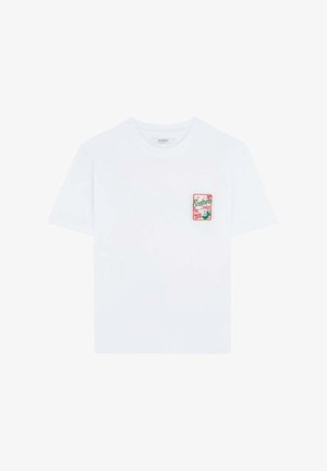 Tricou alb din bumbac cu mâneci scurte, având un patch brodat colorat pe partea stângă a pieptului, cu elemente de design tropical.