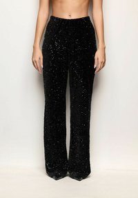 Pantaloni larghi neri in paillettes con una texture liscia, vita alta e vestibilità morbida, caratterizzati da abbellimenti luccicanti su tutta la superficie.