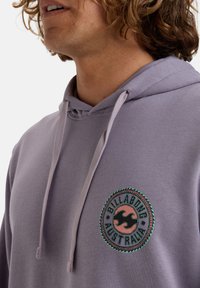 Felpa leggera viola con cappuccio, dotata di un logo ricamato rotondo in rosa e turchese, con cordino e una texture di tessuto morbida.
