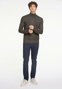 Mörkgrå höghalssweater i mjukt tyg, kombinerad med marinblå byxor och ljusa sneakers. Enkelt, figurnära snitt med ribbade detaljer.