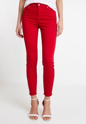 Jean skinny rouge en tissu mélangé coton ; présente une fermeture à bouton et zip à l'avant, des passants de ceinture, et une texture lisse et raffinée.