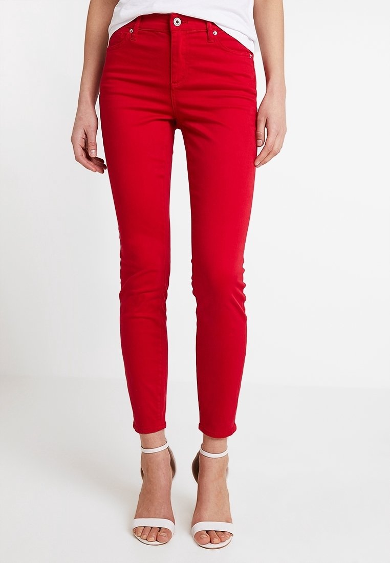 Jeans skinny rossi realizzati in tessuto di cotone misto; presentano una chiusura frontale con bottone e zip, passanti per cintura e una texture liscia e slanciata.