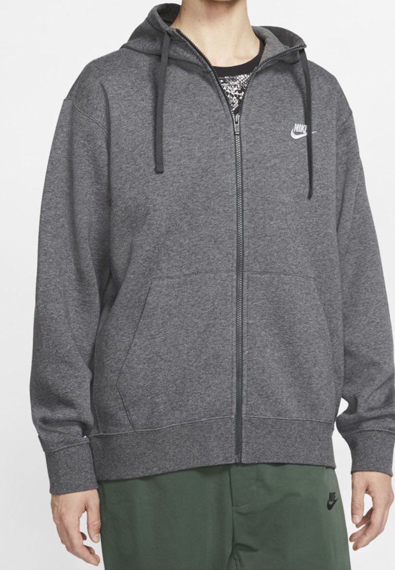 Šedá zipová mikina vyrobená z měkké látky, se staženou kapucí, předními kapsami a malým bílým logem Nike na levé straně hrudníku.