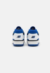 Witte en blauwe sportschoenen met een gewatteerde blauwe kraag, zwarte accenten en gestructureerde zolen. New Balance-logo op de achterkant in het zwart.