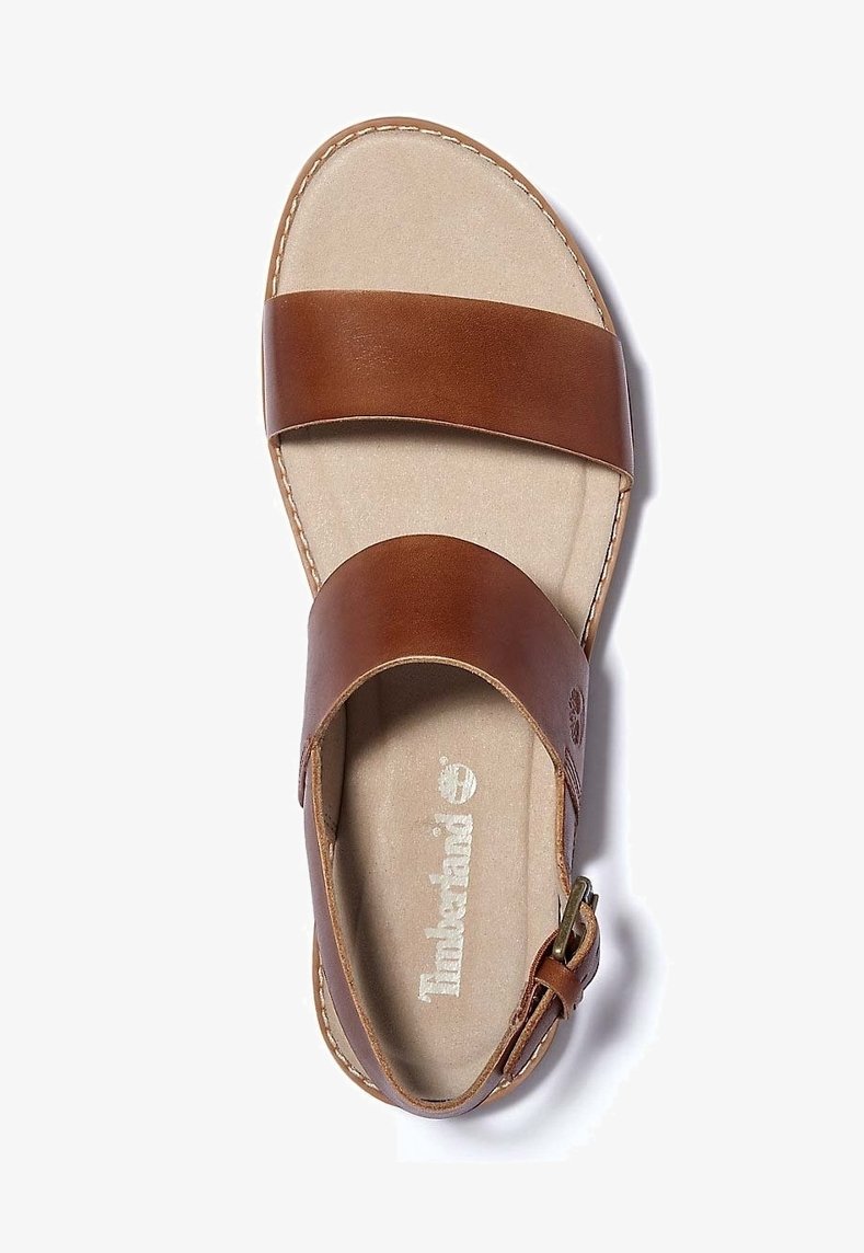 Sandale en cuir marron avec deux larges brides, une boucle sur la bride de la cheville, et une semelle intérieure beige rembourrée avec le logo Timberland.