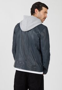 Navy Lederjacke mit grauer Kapuze, ausgestattet mit einer strukturierten Oberfläche, taillierter Silhouette und Nahtdetails. Geeignet für legere Anlässe.