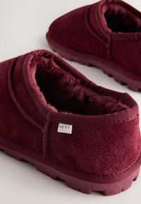 Pantofole slip-on bordeaux in morbido tessuto, con interno morbido e suola in gomma testurizzata con una piccola etichetta con la scritta "NEXT".