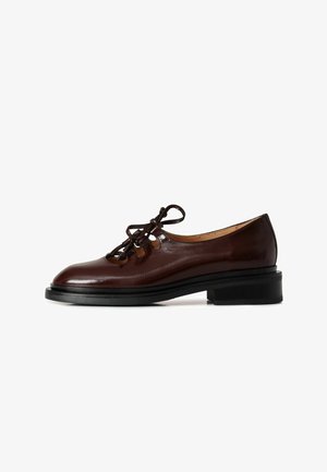 Scarpe in pelle marrone con lacci, dalla finitura liscia, punta arrotondata e tacco nero basso. Presentano dettagli intagliati e lacci decorativi.