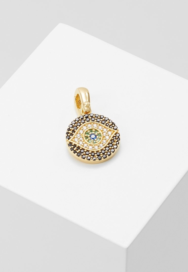 Pendentif en or en forme d'œil, décoré de petites pierres précieuses noires, blanches, vertes et bleues, présenté sur une surface blanche.