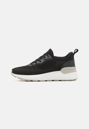Sapatos desportivos pretos com parte superior em malha, detalhes cinzentos e sola branca. Apresenta um calcanhar texturizado e atacadores tonais para um ajuste seguro.
