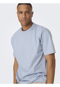 Helles blaues Baumwoll-T-Shirt mit Rundhalsausschnitt, kurzen Ärmeln und lockerer Passform. Glatte Textur ohne sichtbare Muster oder Akzente.