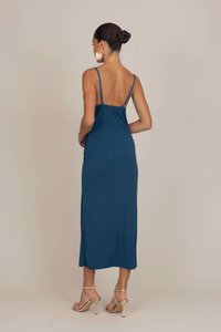 Robe mi-longue sans manches en teal profond, avec une texture côtelée et de fines bretelles. Assortie à des chaussures dorées �à lanières.
