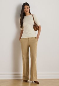 Cream short-sleeve top, beige wide-leg pants, brown handbag, and brown pointed-toe heels. Smooth fabric, simple lines, and neutral color palette.