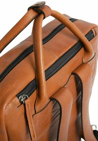 Sac en cuir marron avec deux poignées arrondies, une fermeture éclair sur le dessus et des coutures visibles. La poche latérale présente une texture matelassée.