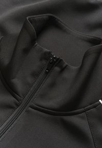 Giacca di tessuto nera con colletto alto e zip centrale nera, che mostra cuciture e texture dettagliate.