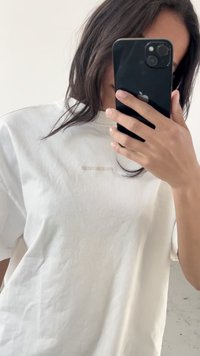 T-shirt bianco in cotone con maniche corte, caratterizzato da un logo testurizzato sottile di colore chiaro sul petto e una vestibilità rilassata.