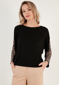 Black long-sleeve top with leopard print accents on the sleeves. Made of soft fabric, featuring a loose fit and a round neckline.