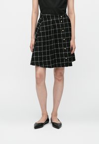 Fekete kockás szoknya fehér rácsos mintával, texturált anyagból készült, az oldalon arany gombokkal, térd hosszúságú fazon.