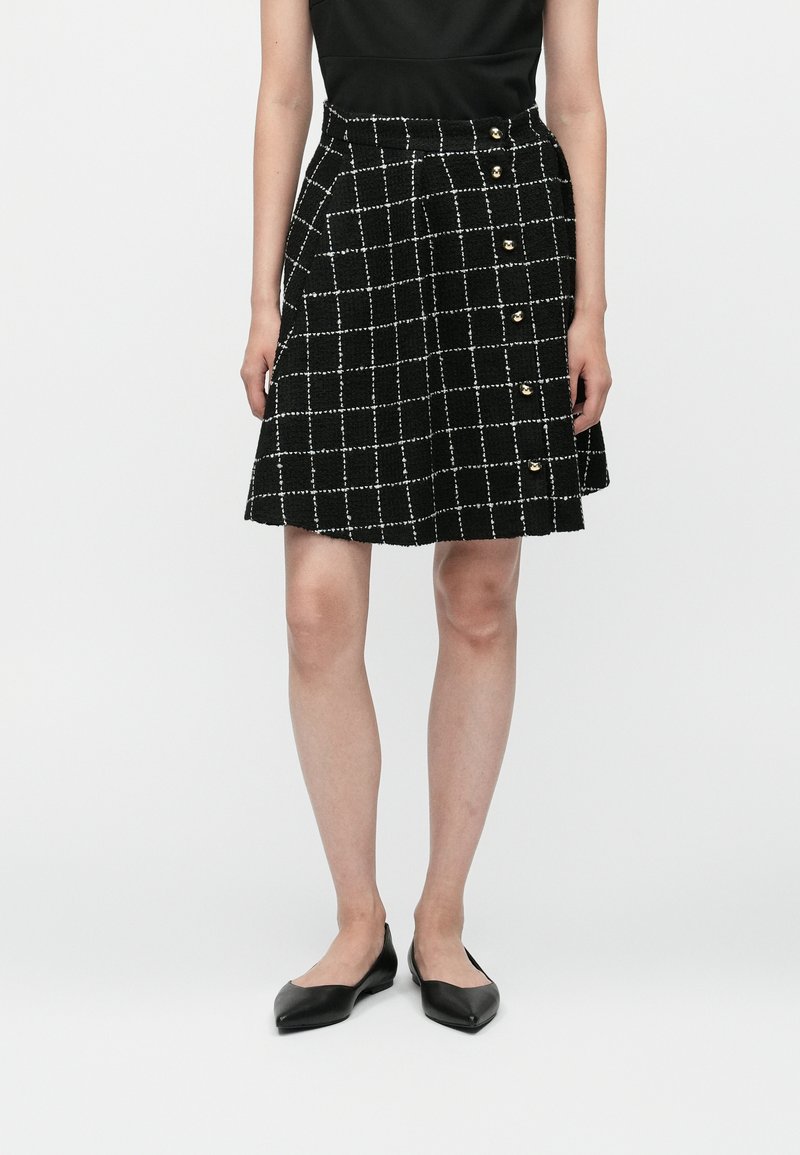 Fekete kockás szoknya fehér rácsos mintával, texturált anyagból készült, az oldalon arany gombokkal, térd hosszúságú fazon.